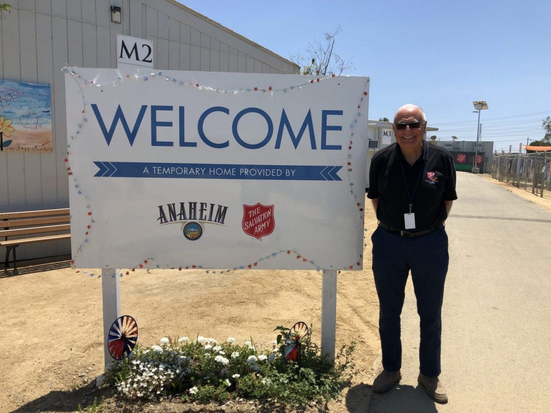 Man standing in front of sign that says welcome