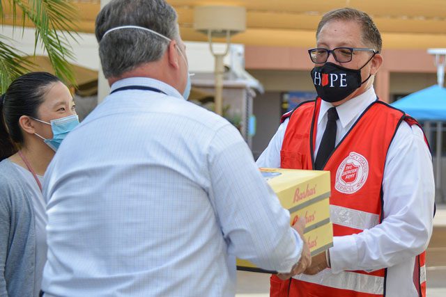 man in mask passing boxes to other man