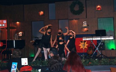 A group of young dancers performs a dance on stage at a Christmas event.