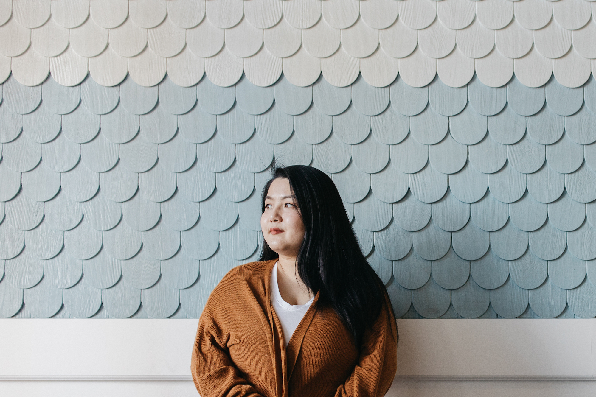 woman standing in from of a blue wall slightly smiling