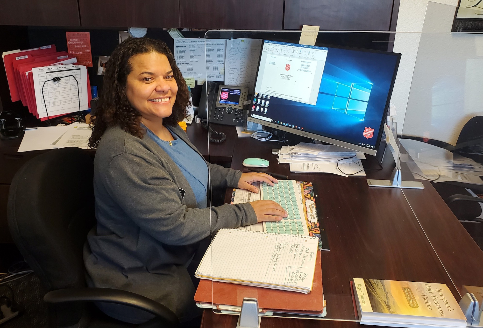 Woman smiling and sitting at a desk with a computer