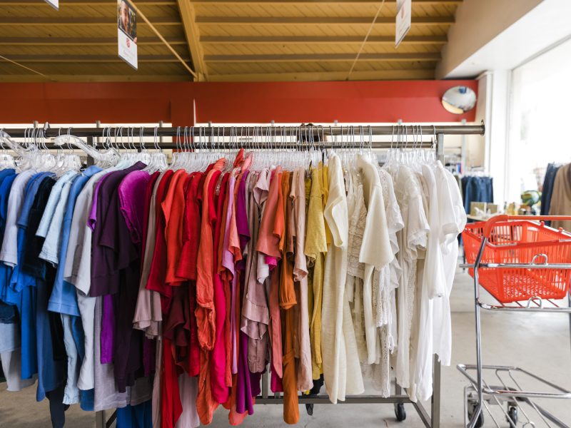 rack of clothing in a thrift store organized by color
