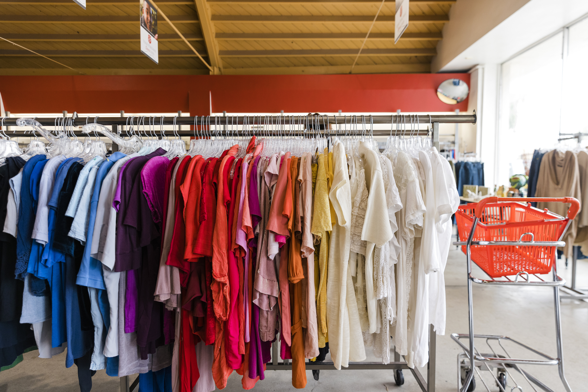 rack of clothing in a thrift store organized by color