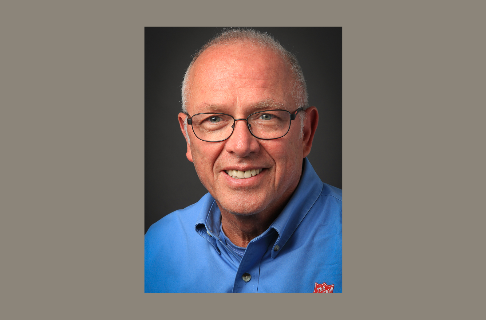 Salvation Army Emergency Disaster Services Director John Berglund smiles for a portrait wearing a blue shirt and glasses