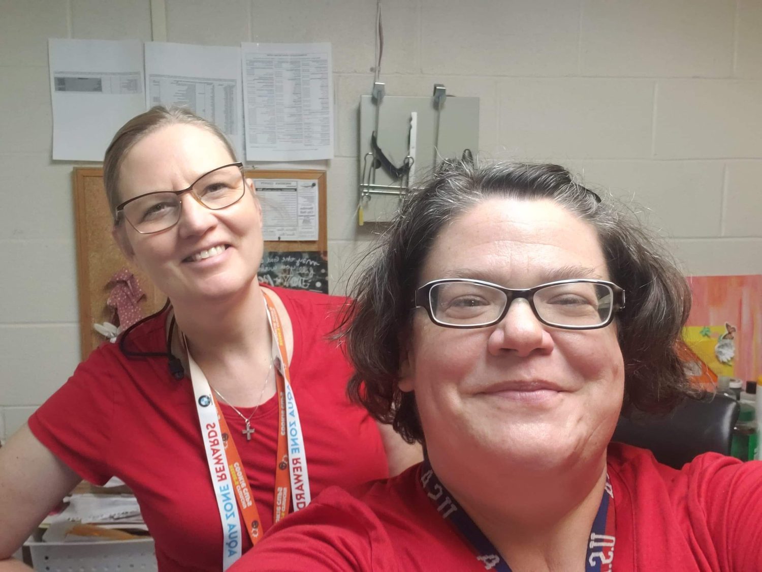two women wearing red shirts smile for a selfie