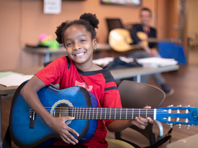 young girl smiling with a guitar