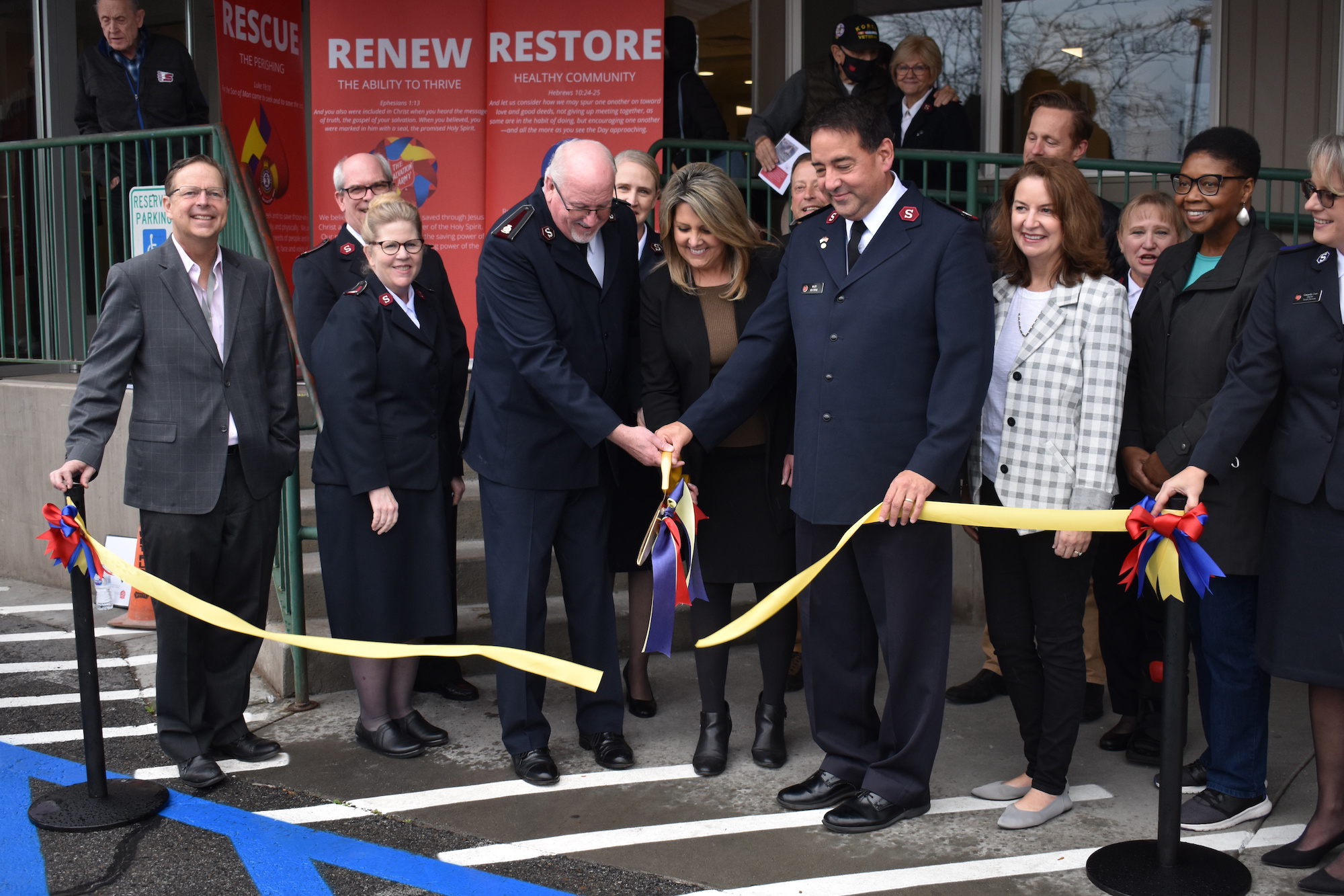 men and women participate in a ribbon cutting ceremony